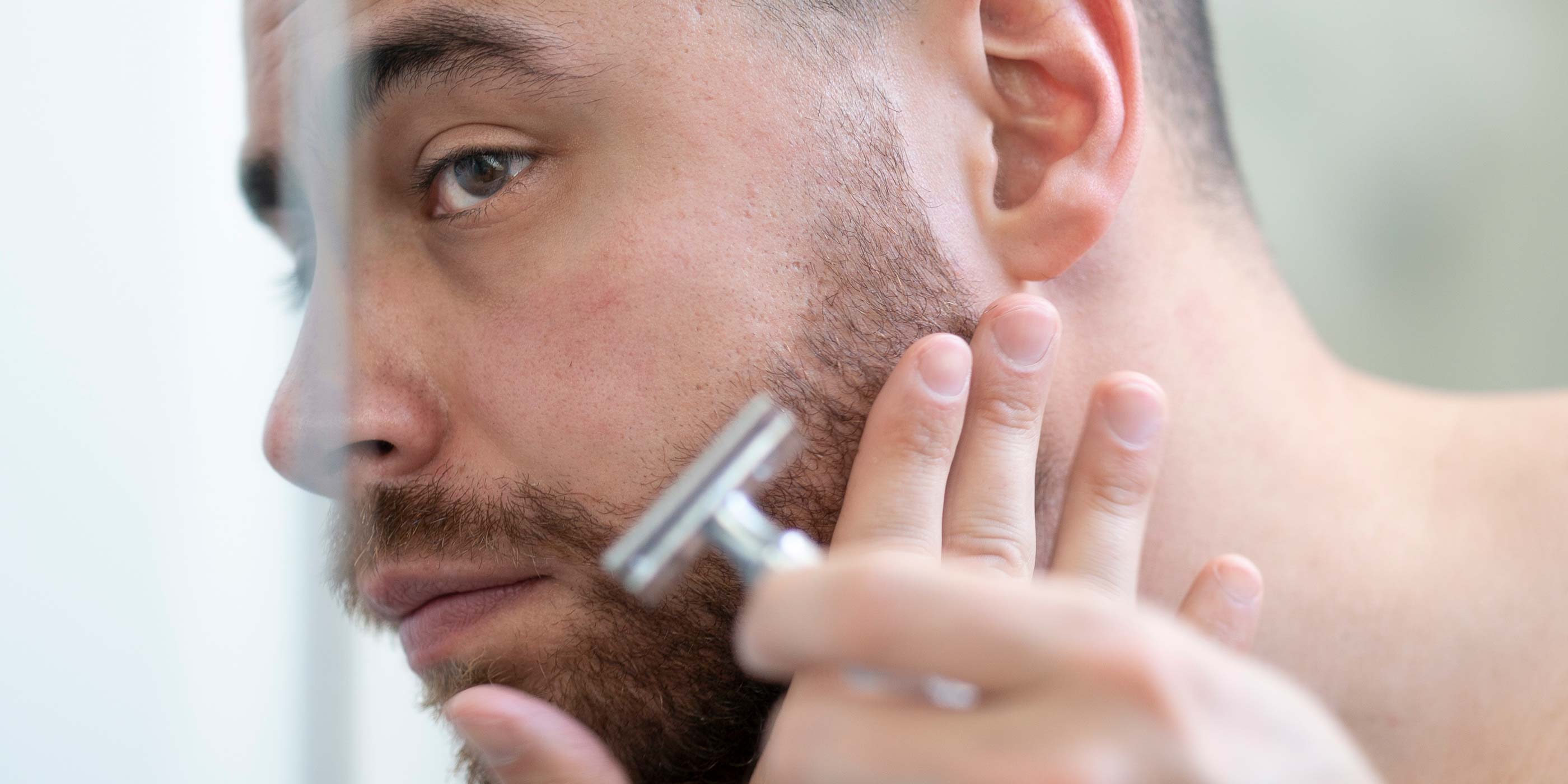 Mann som barberer linjene rundt skjegget