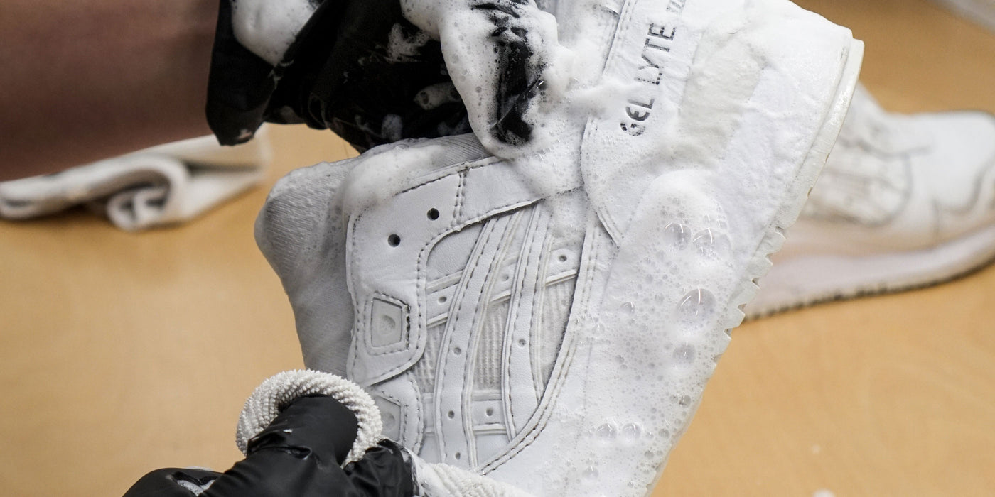 Nærbilde av vask av hvite joggesko med rensemiddel.