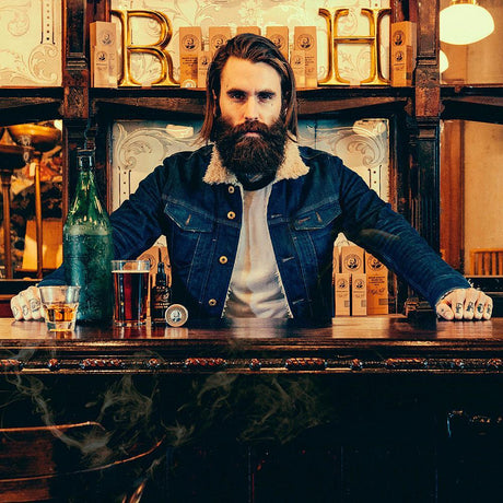 Mann med skjegg bruker Captain Fawcett Beard Oil Booze & Baccy i bar